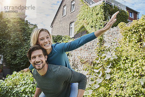 Porträt eines glücklichen Paares im Garten ihres Hauses