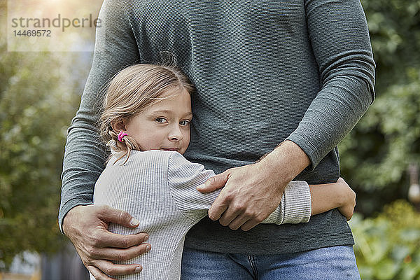 Porträt eines Mädchens  das seinen Vater im Garten umarmt