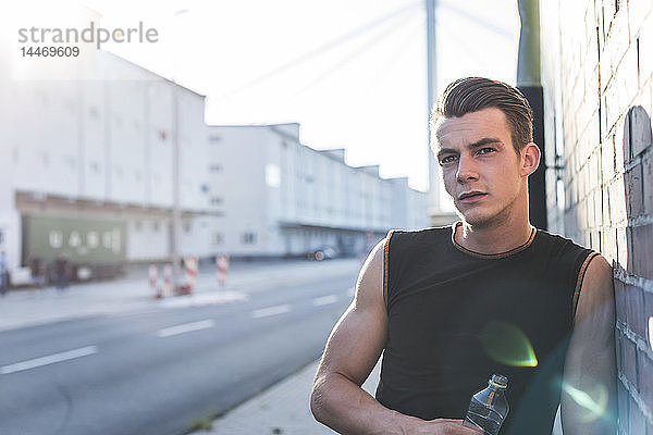 Deutschland  Mannheim  Junger Sportler in der Stadt mit Wasserflasche  Portrait