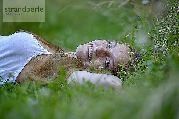 Porträt einer glücklichen Teenagerin  die sich im Sommer auf einer Wiese entspannt