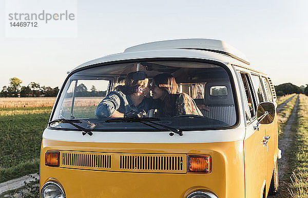 Glückliches Paar sitzt in seinem Wohnwagen und küsst sich
