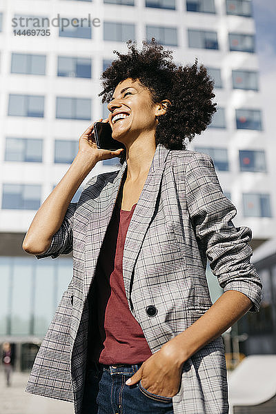 Lachende Geschäftsfrau am Handy vor dem Bürogebäude