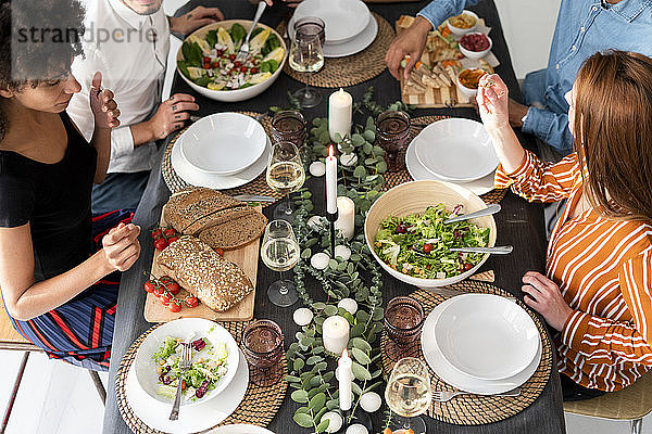 Freunde sitzen am gedeckten Tisch  genießen ihre Dinnerparty  Blick von oben