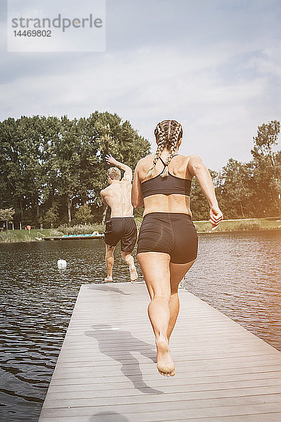 Sportler  die auf einem Steg laufen  nach dem Training in einen See springen