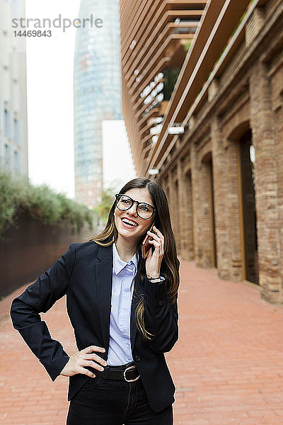 Glückliche junge Geschäftsfrau am Handy in der Stadt