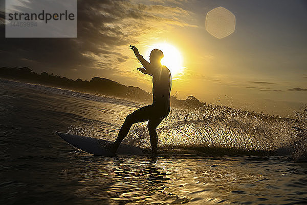 Indonesien  Bali  Canggu  Silhouette eines Surfers bei Sonnenuntergang