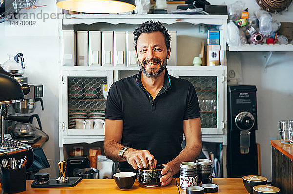 Porträt eines lächelnden Barista an der Theke eines Cafés