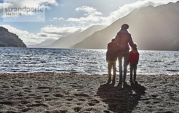 Argentinien  Patagonien  Lago Nahuel Huapi  Frau mit zwei Söhnen  die am Ufer mit Blick auf den See stehen