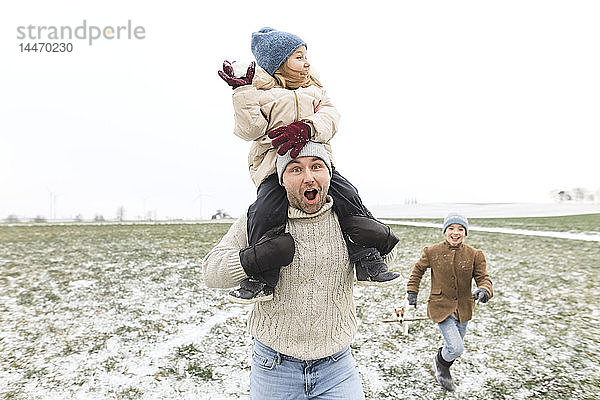 Glücklicher Vater mit zwei Kindern in Winterlandschaft