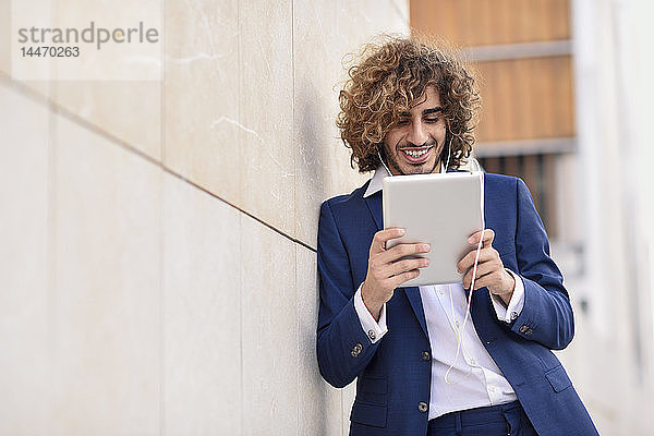 Porträt eines jungen Geschäftsmannes  der ein digitales Tablet im Freien benutzt