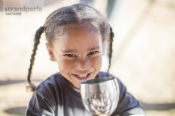 Porträt eines lächelnden Mädchens  das aus einem Kelch trinkt