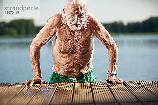 Porträt eines älteren Mannes  der sich am Steg am See anlehnt