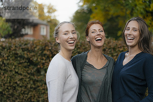 Porträt einer glücklichen Mutter mit zwei Teenager-Mädchen im Garten