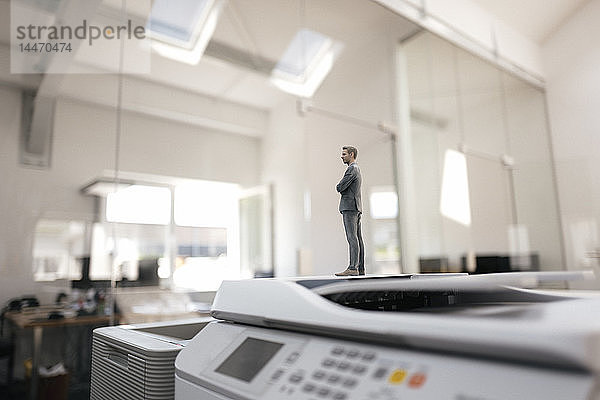 Geschäftsmann-Figur steht auf Kopiergeräten im modernen Büro