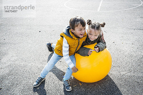 Zwei kleine Kinder haben Spaß am Gymnastikball