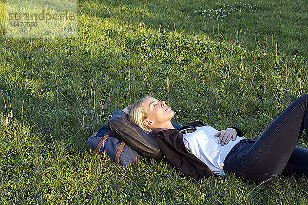 Frau liegt auf einer Wiese in einem Park und entspannt