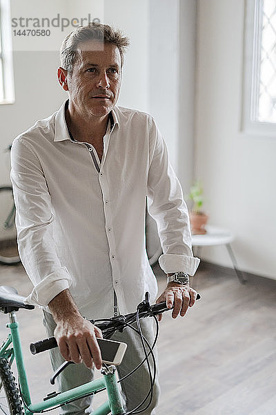 Porträt eines Geschäftsmannes mit Fahrrad im Büro