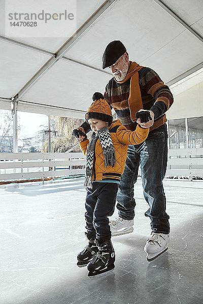 Grossvater und Enkel auf der Eisbahn  Schlittschuhlaufen