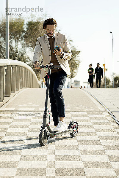 Mann mit E-Scooter und Mobiltelefon in der Stadt  Teilansicht
