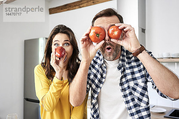 Ein Paar  das sich in der Küche vergnügt und mit Tomaten spielt