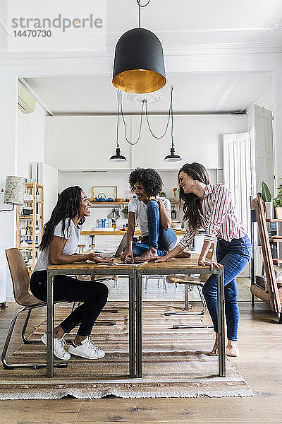 Drei glückliche Frauen sprechen zu Hause am Tisch