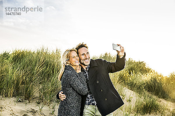 Glückliches Paar in den Dünen beim Selfie