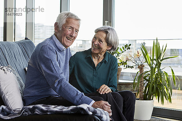 Lachendes Seniorenpaar sitzt zusammen auf der Couch