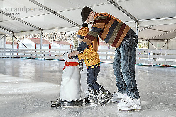 Grossvater und Enkel auf der Eisbahn  Schlittschuhlaufen  mit Eisbärenfigur als Requisite