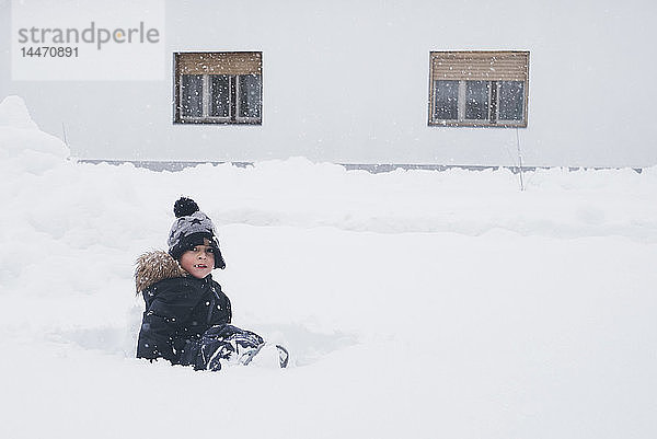 Porträt eines im Schnee sitzenden Kleinkindes