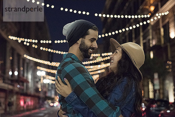 Glückliches junges Paar umarmt sich nachts auf der Straße