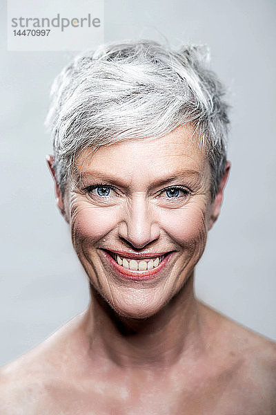 Bildnis einer lachenden  reifen Frau mit kurzen  grauen Haaren und blauen Augen