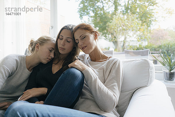 Mutter mit zwei Teenager-Mädchen  die sich zu Hause auf der Couch entspannen