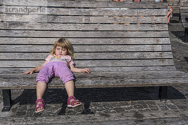 Schweden  Mädchen auf Holzbank auf dem Stadtplatz liegend