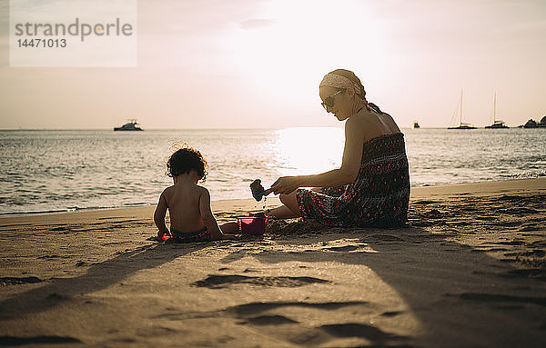 Thailand  Koh Lanta  Mutter spielt mit kleiner Tochter am Strand bei Sonnenuntergang