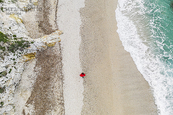 Italien  Elba  Frau mit rotem Mantel beim Strandspaziergang  Luftaufnahme mit Drohne