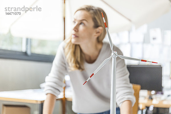 Frau im Büro arbeitet am Modell einer Windkraftanlage