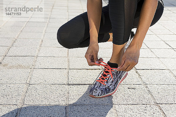 Nahaufnahme einer jungen Frau  die sich vor dem Training die Schuhe zubindet