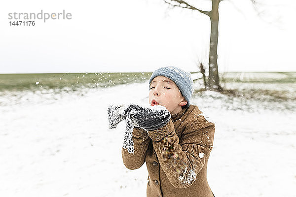 Junge spielt im Winter mit Schnee