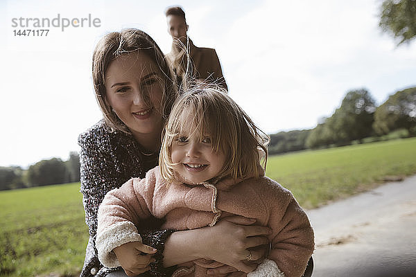 Porträt eines glücklichen blonden kleinen Mädchens in den Armen seiner Mutter