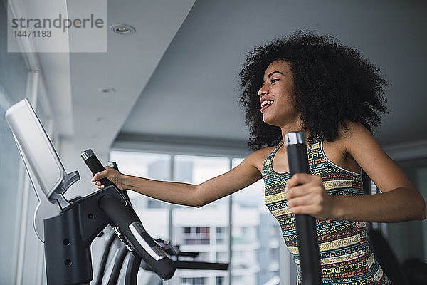 Lächelnde junge Frau auf Schrittmaschine im Fitnessstudio
