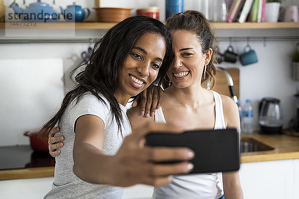Zwei glückliche Freundinnen machen zu Hause ein Selfie