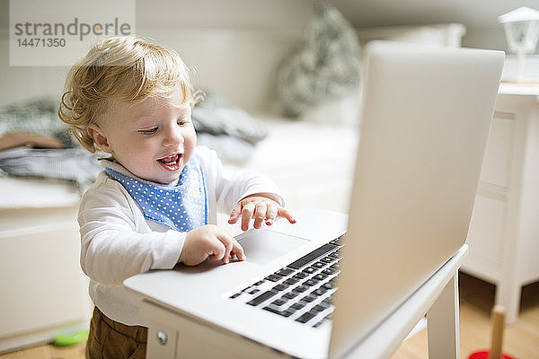 Kleiner Junge spielt zu Hause mit Laptop