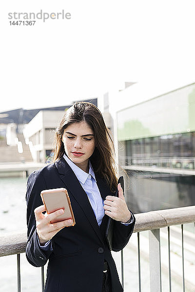 Junge Geschäftsfrau benutzt Handy in der Stadt