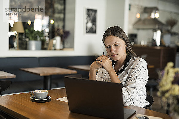 Junge Geschäftsfrau in einem Café  die mit einem Laptop auf einem Holztisch arbeitet