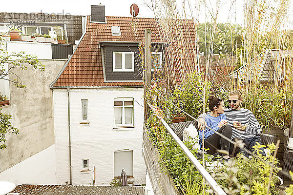 Junges Paar entspannt sich auf dem Balkon  auf der Couch sitzend