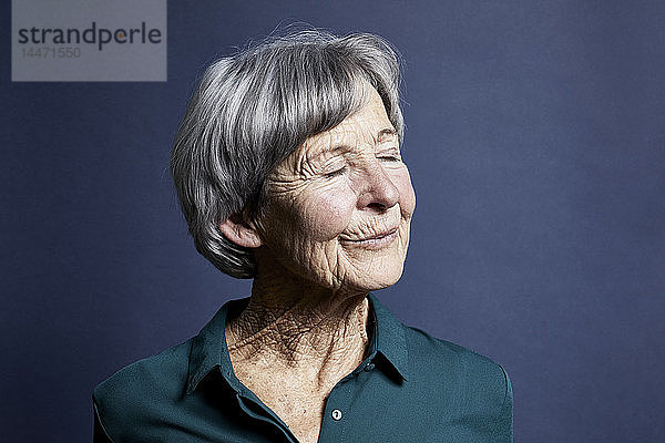 Porträt einer lächelnden älteren Frau mit geschlossenen Augen