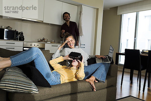 Freunde sitzen auf der Couch im Wohnzimmer  spielen mit VR-Brille