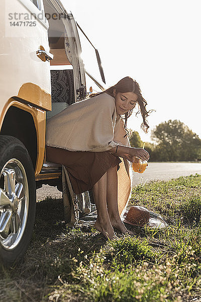 Hübsche Frau auf einer Autoreise mit ihrem Wohnmobil  macht eine Pause  trinkt Saft
