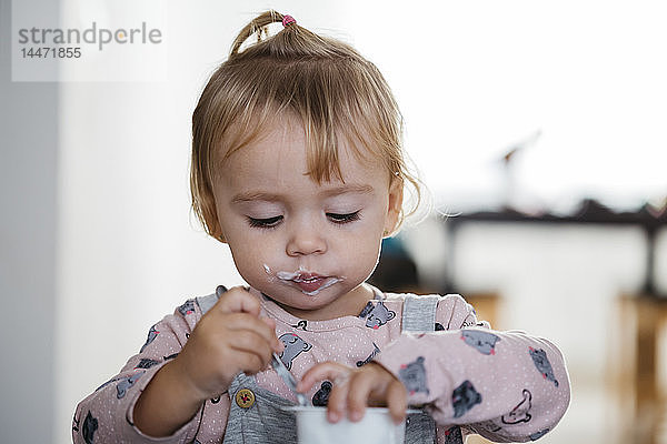 Porträt eines kleinen Mädchens  das zu Hause Joghurt isst