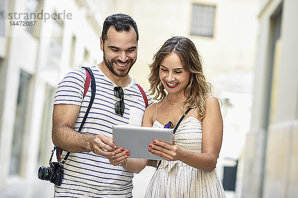 Spanien  Andalusien  Malaga  glückliches Touristenpaar in der Stadt beim Blick auf die Tablette